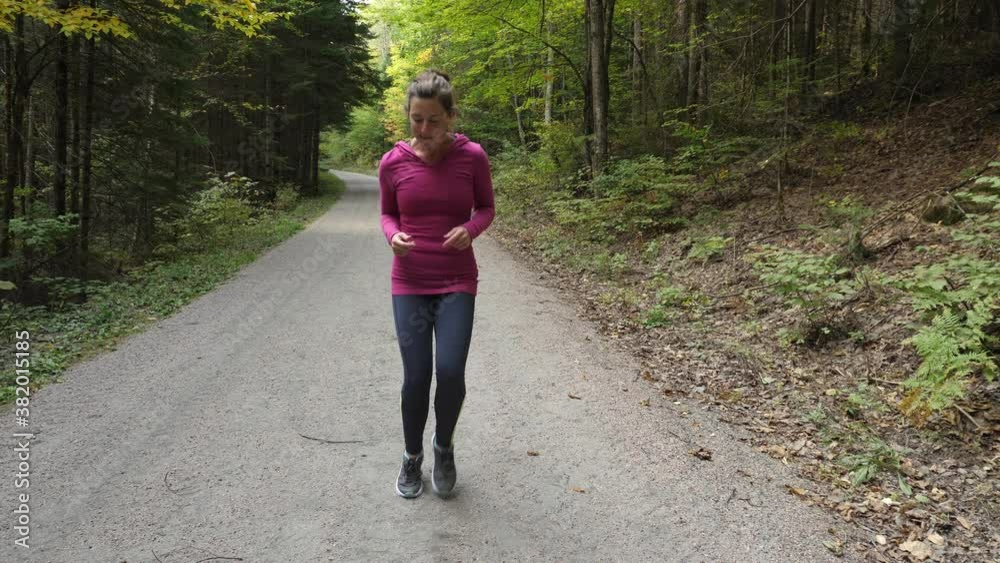 Athletic 40s woman running on spot. Warming up. Forest trail. Facing. Athletic 40s woman running on spot. Warming up. Forest trail. Facing.