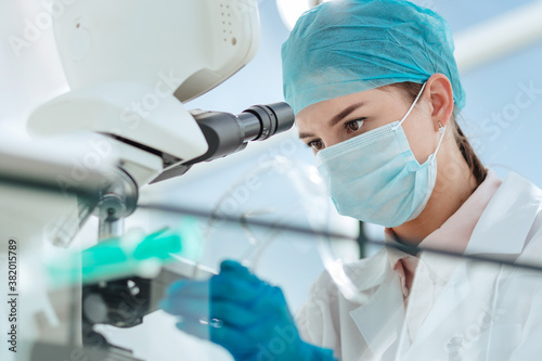 close up. female researcher looking through a microscope.