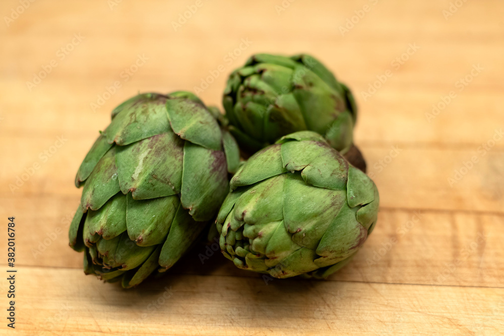 Obraz premium baby artichokes on a wooden background cutting board