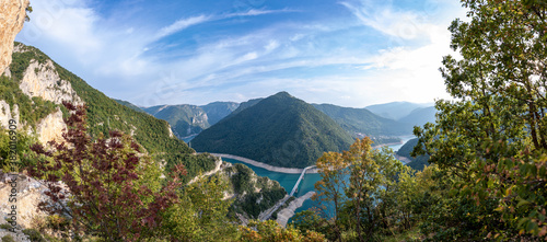 Massive panorama of Lake Piva or Pivsko jezero in Montenegro. View to the bridge from Durmitor to Pluzine town. Unbelievable serpentine road with tunnels. Lovely blue sky with clouds.