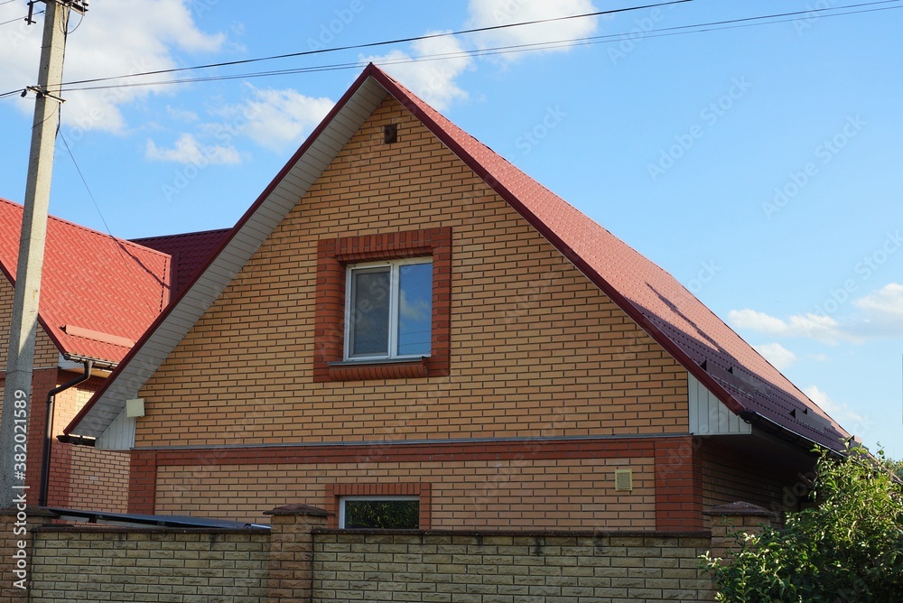 attic of a private rural house made of brown bricks with one window against a blue sky