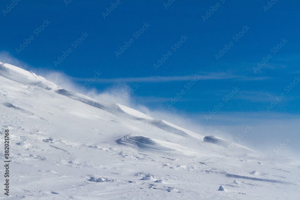 .Snowy mountain slope with wind, winter background