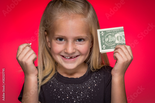 Little Girl Holding Tooth and Dollar Bill Smiling With Missing Tooth photo