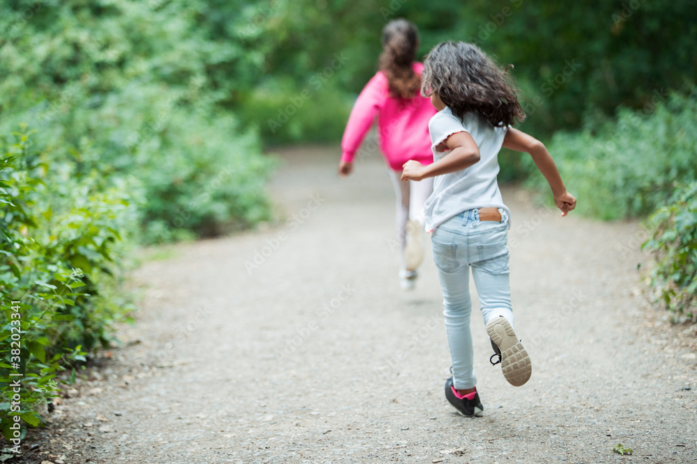 Carefree sisters running on park path Carefree sisters running on park path