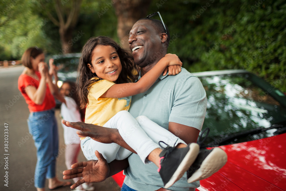 © Paul Bradbury/Caia Image - Happy father holding daughter outside convertible