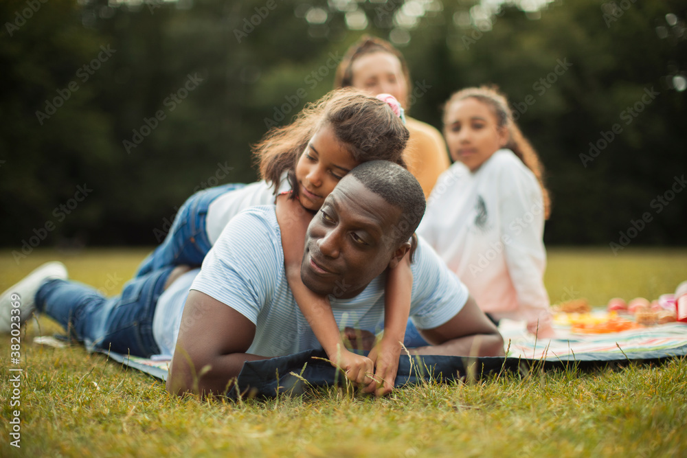 Affectionate daughter hugging father on picnic blanket in park Affectionate daughter hugging father on picnic blanket in park