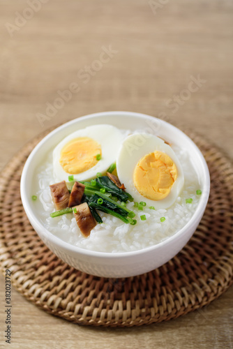 Asian food  Rice soup with boiled egg  grilled mushroom and spinach in a bowl on woven rattan sheet