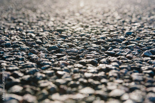 Close-up in focus Texture, surface of rough asphalt. Side view of a dark gray granular road.