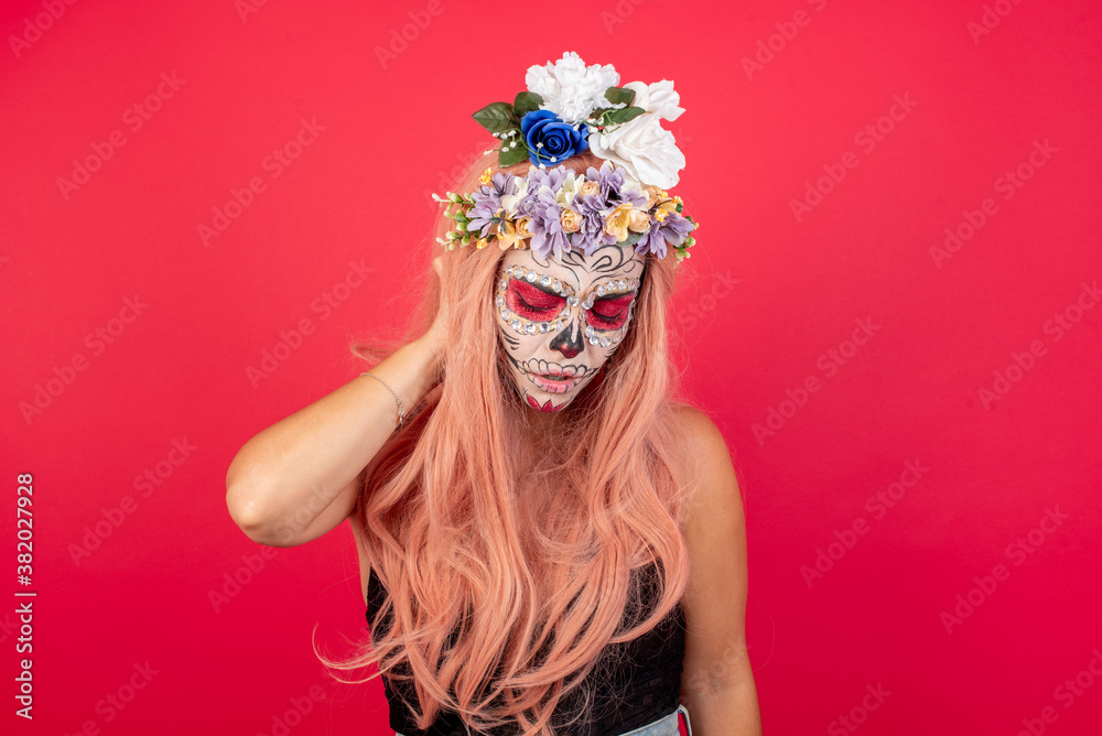 young beautiful woman wearing halloween make up over red studio background Suffering of neck ache injury, touching neck with hand, muscular pain