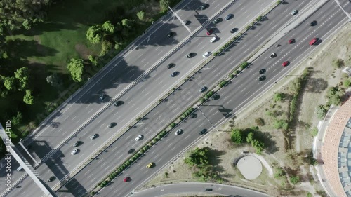general angular plane drone traveling straight ahead in road air with cars traffic trucks transportation city rounds with trees and forest madrid spain with traffic jam cars passing driving