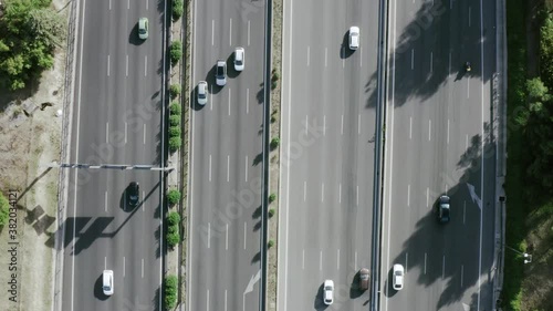 general angular plane drone traveling straight ahead in road air with cars traffic trucks transportation city rounds with trees and forest madrid spain with traffic jam cars passing driving