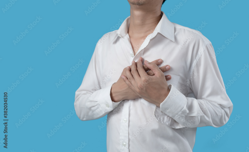 Man holding hands on chest suffering from heart attack on blue background Man holding hands on chest suffering from heart attack on blue background