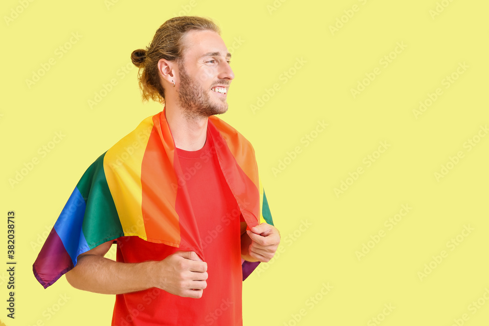 Young man with LGBT flag on color background Young man with LGBT flag on color background
