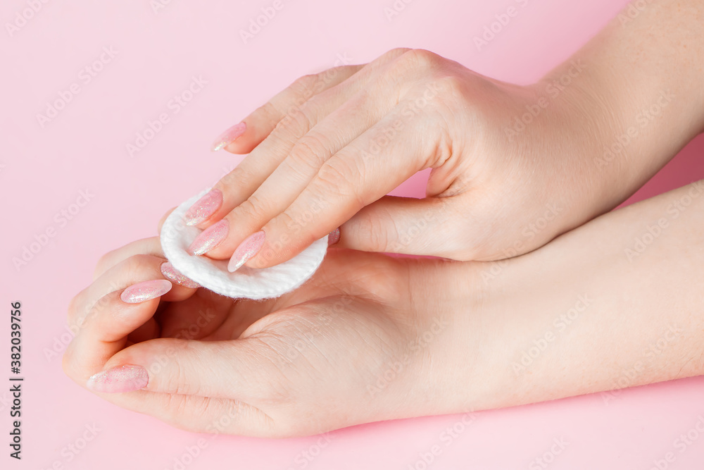 Hand care concept. Young woman remove nail polish on pink background. Place for text. Hand care concept. Young woman remove nail polish on pink background. Place for text.