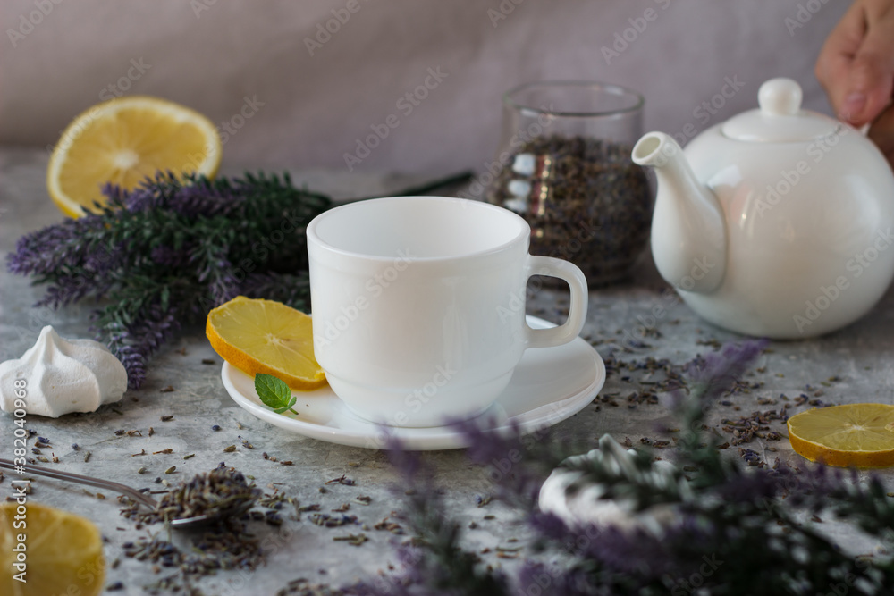 lavender tea in a white mug. Purple tea in a mug on a light background stands on the table next to lavender flowers lavender tea in a white mug. Purple tea in a mug on a light background stands on the table next to lavender flowers