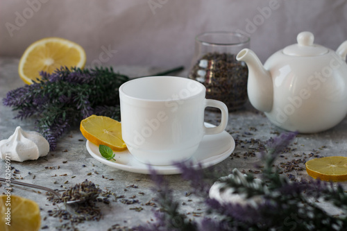 lavender tea in a white mug. Purple tea in a mug on a light background stands on the table next to lavender flowers