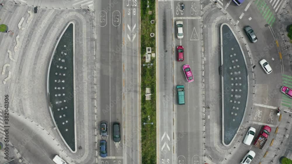 Aerial birds eye view of a roundabout with cars, bicycles, buses and people walking by. Going up Mexico city Manacar