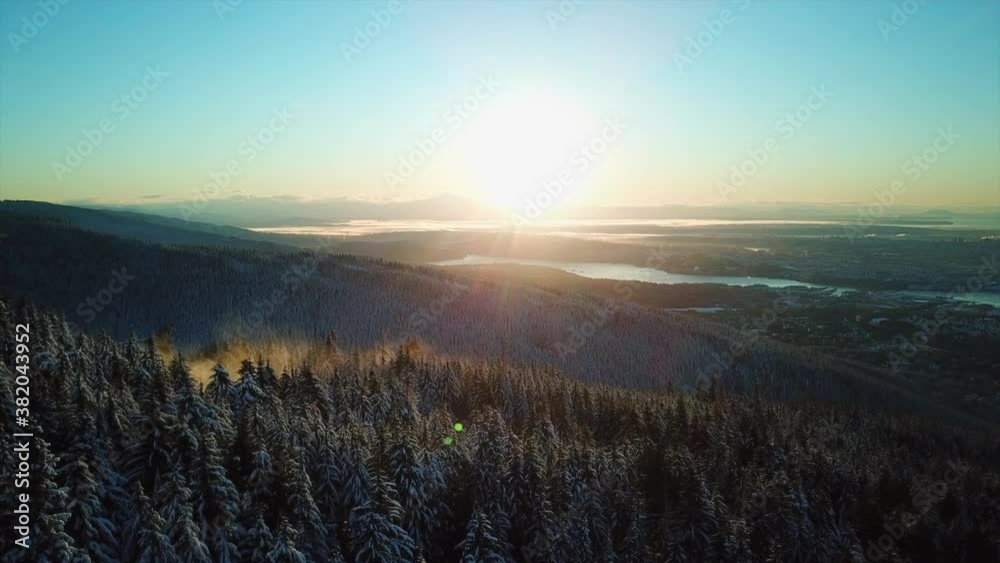 Sunrise over snow covered pine trees and small cloud of fog forming, aerial Sunrise over snow covered pine trees and small cloud of fog forming, aerial
