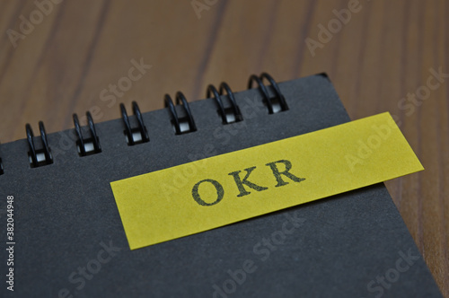 Sticky notes stamped with the initials "Objectives and Key Results (OKR)" are taped to the edges of the notebooks.