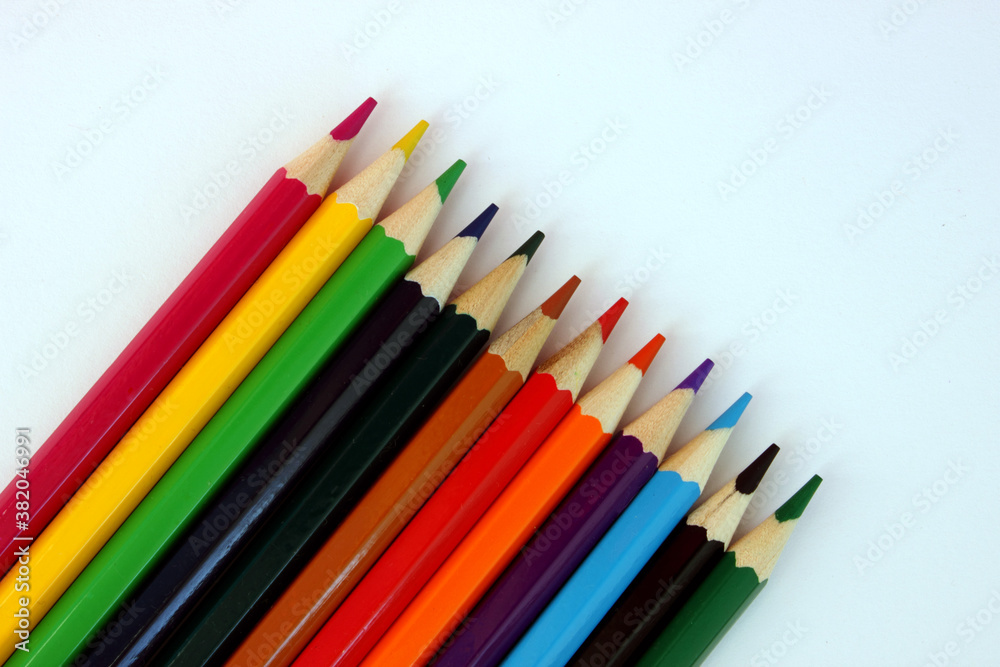 Colored pencils on a white background. Lots of different colored pencils. Colored pencil. Pencils are sharp. Pencils lie diagonally in the lower left corner. Close-up. Copy space. Background. Flat lay