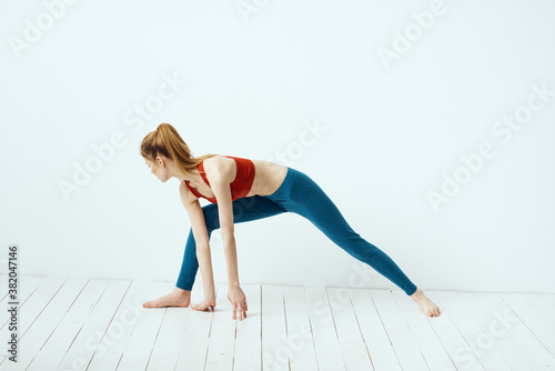 athletic woman in pose on the floor exercise gymnastics performance light background