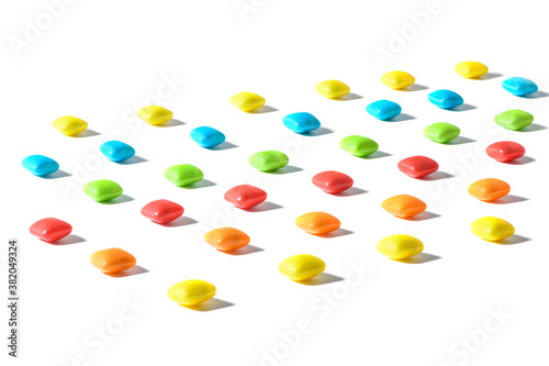 Colorful candies , dragee, chewing gum are placed in a row with a contrasting shadow on a white isolated background with focus stacking. Advertising label design element. Full depth of field. .