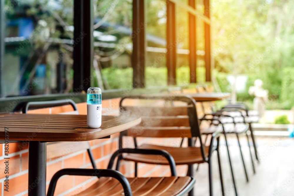 Fototapeta premium Alcohol nano mist sprayer for hand cleaning to prevent the spread of the Corona virus (Covid-19) to serve customers at coffee shop. Modern health technology. New normal lifestyle. Selective focus