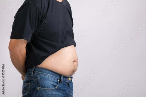 Medical check up concept : Fat people showing his big belly. Used for liver problem or Obesity concept. Studio shot on grey