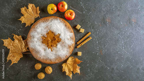 Homemade apple pie, cobbler, charlotte with walnut and cinnamon. Thanksgiving dish and fall dry leaves on rustic table. Autumn harvest festival. Copy space for text
