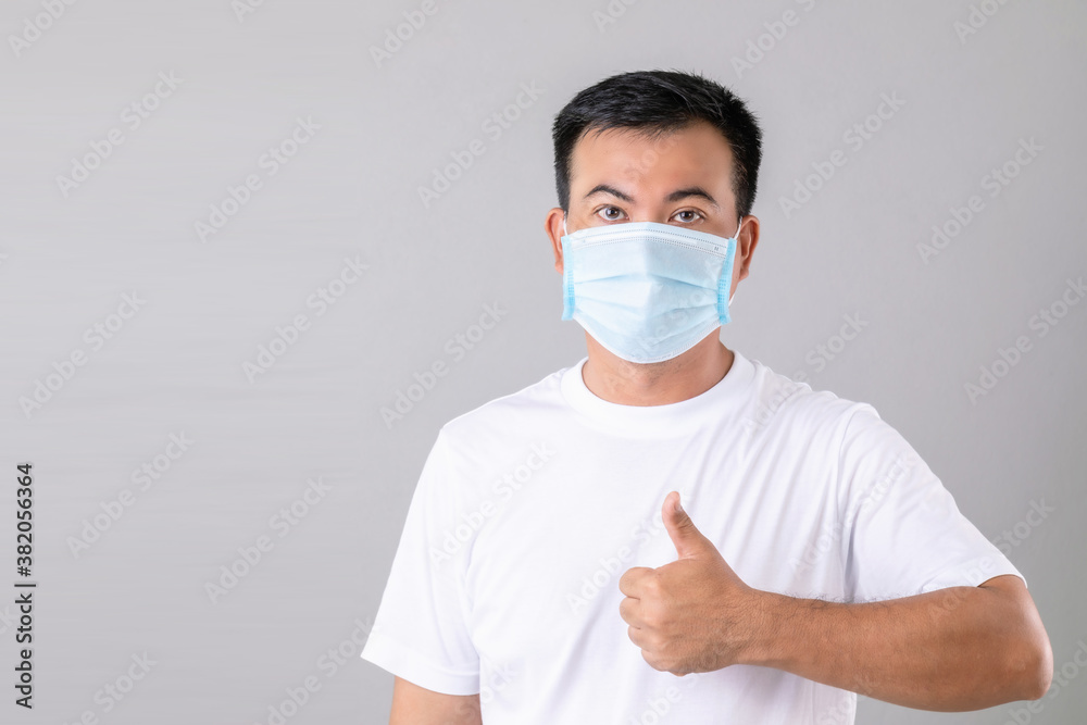 Thai man wearing protective face mask to prevent virus studio shot on grey background Thai man wearing protective face mask to prevent virus studio shot on grey background