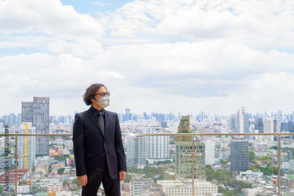 Portrait of Japanese businessman wearing mask and thinking against view of the city Portrait of Japanese businessman wearing mask and thinking against view of the city