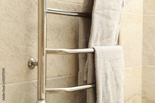 Modern heated towel rail on tiled bathroom wall photo