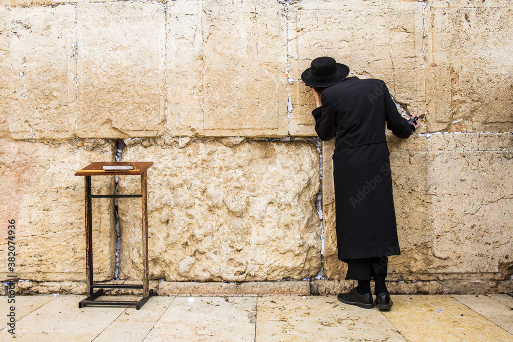 Western wall jew in black praying at the wall