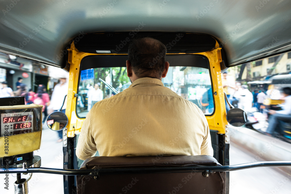 Mumbai, India, 10 january 2020 - Sitting in the back of a typical indian tuk tuk, looking at the indian driver's back while touring the busy streets of Mumbai. International tourism.