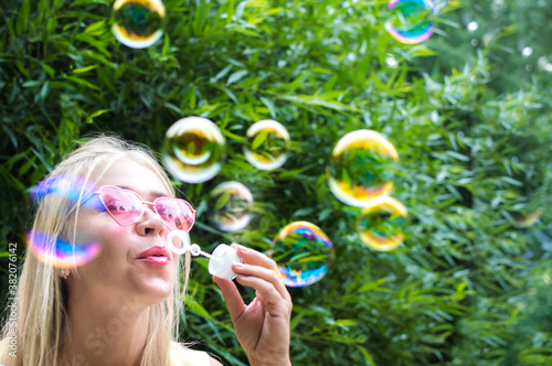 Young woman blows soap bubbles in the street. Close-up portrait. Happiness and positive emotions concept. Soft focus