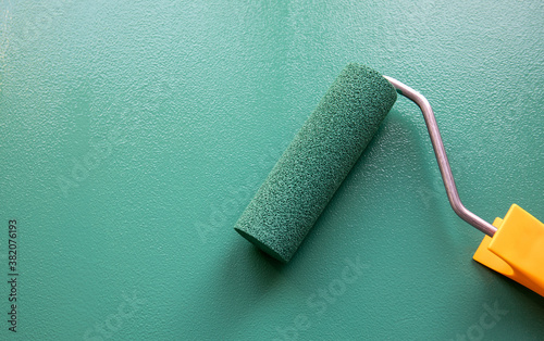 Fototapeta Naklejka Na Ścianę i Meble -  Paint roller with green colour on painted wooden surface. Chalk board
