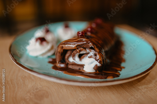 chocolate pancake with bananas, nuts and chocolate sauce. the toning. selective focus. a rolled chocolate pancake is a calorie bomb