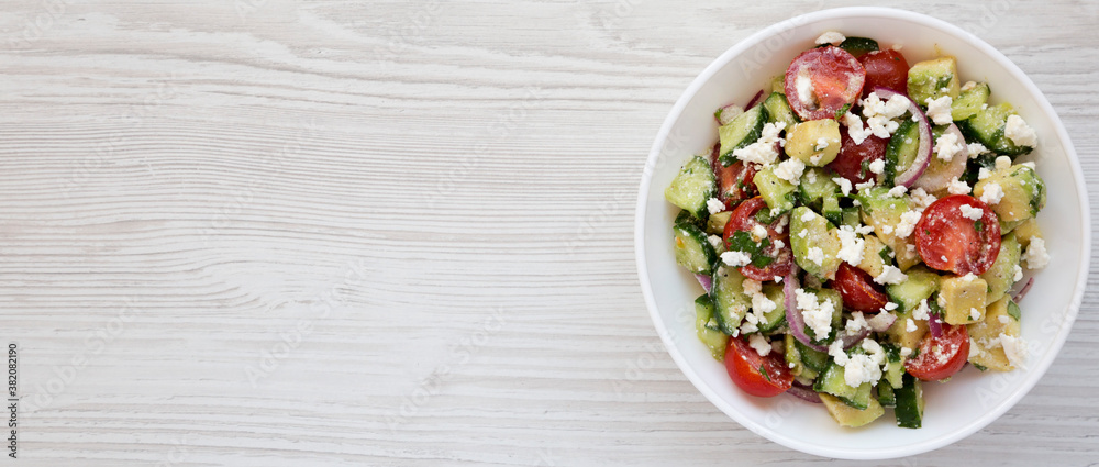 Tasty Avocado Tomato and Cucumber Salad in a bowl on a white wooden surface, top view. Space for text. Tasty Avocado Tomato and Cucumber Salad in a bowl on a white wooden surface, top view. Space for text.