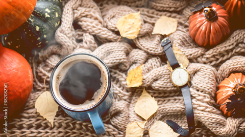 Autumn background with dry leaves, blue cup of coffee. Knitted background, pumpkins, October, November. Autumnal atmosphere. Autumn season.