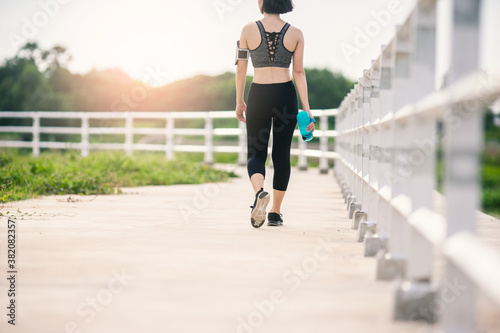 Beside of woman in sportswear fitness holding bottle water she is walking. © ME Image