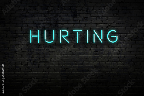 Night view of neon sign on brick wall with inscription hurting