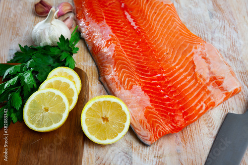 Image of appetizing raw salmon fillet with lemon and greens before cooking
