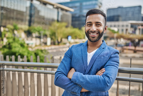 Portrait of smiling Indian Arabic businessman arms crossed in the city