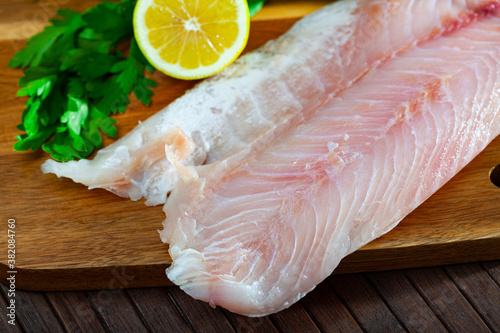 Image of fillet of raw perch fillet before cooking with greens on wooden background