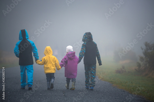 Foto Four children, siblings boys and girl, walking on a rural path on a foggy autumn