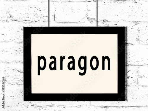 Black frame hanging on white brick wall with inscription paragon