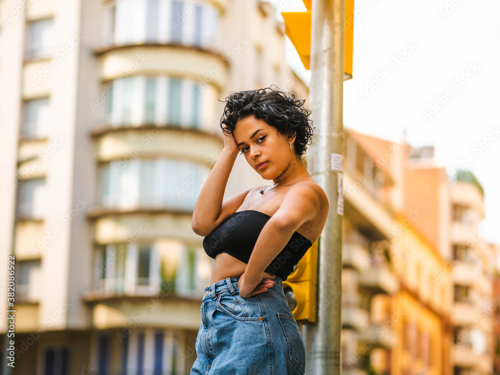 Brazilian woman with headphones in the street. woman sitting on the roof with a modern building in the background