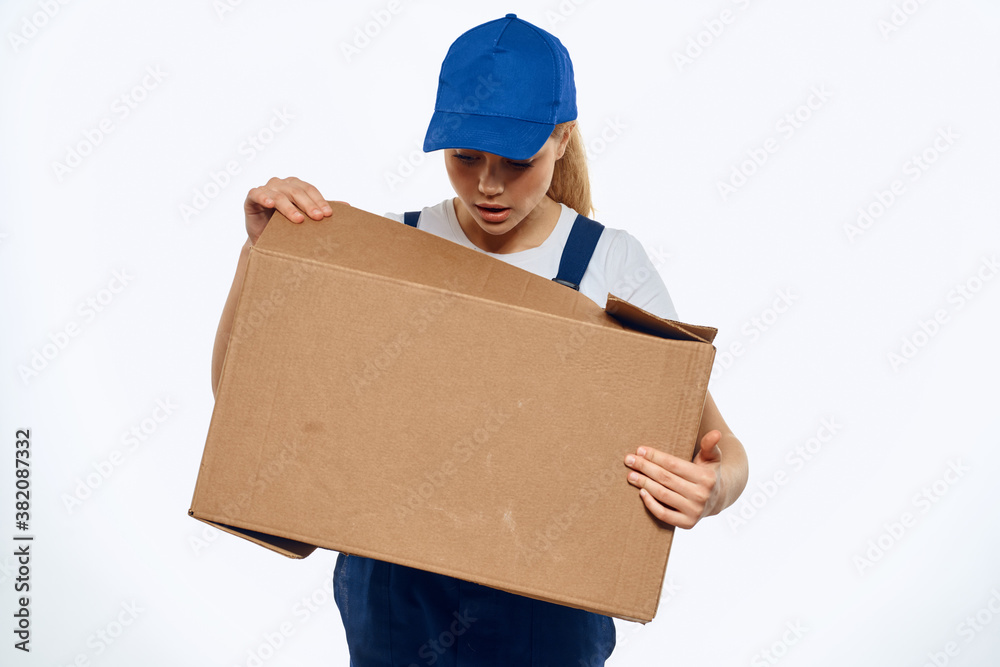 A woman in a working uniform with a box in the hands of a delivery service delivery service light background A woman in a working uniform with a box in the hands of a delivery service delivery service light background
