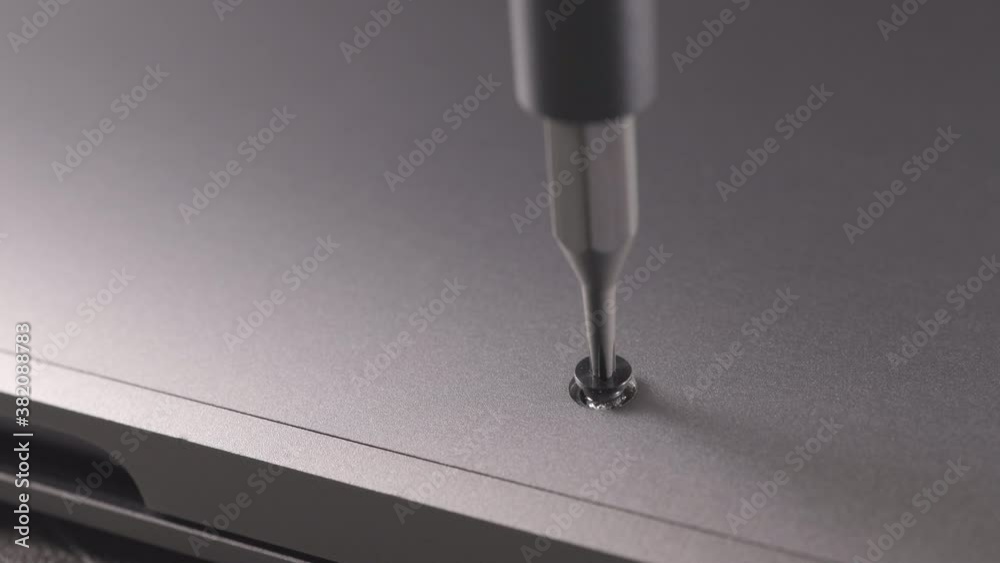 an electronics repairman unscrews and tightens a screw with a screwdriver
