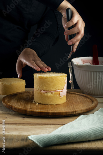Vertical shot of a person preparing a small vanilla cake